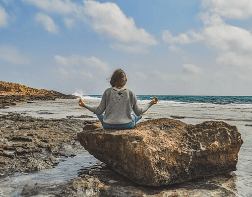 Sénior assise en tailleur sur un rocher bienfaits du yoga pour les seniors